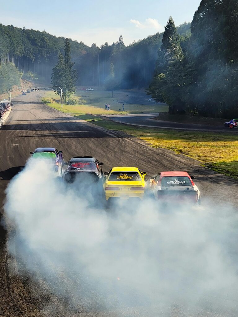 Four drift cars creating smoke on a racing track in Aichi, Japan.